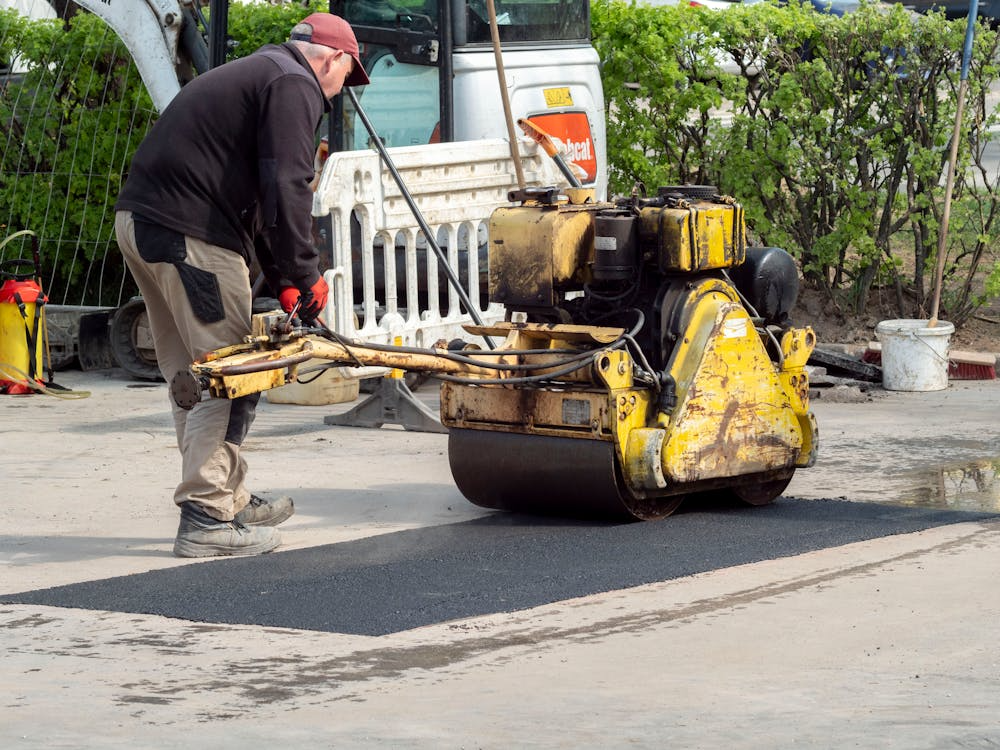 A construction worker operating machinery while repairing cracks in a concrete surface.