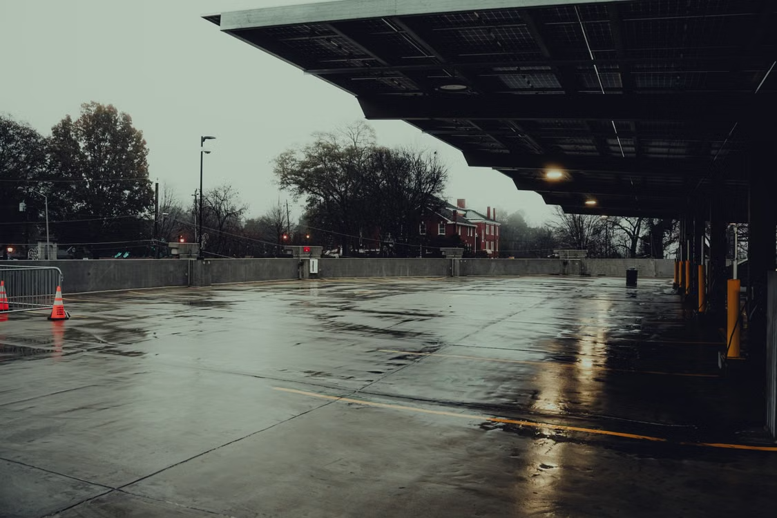 An empty parking lot with wet, reflective pavement after rain