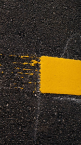A close-up of a broken yellow line on cracked asphalt pavement