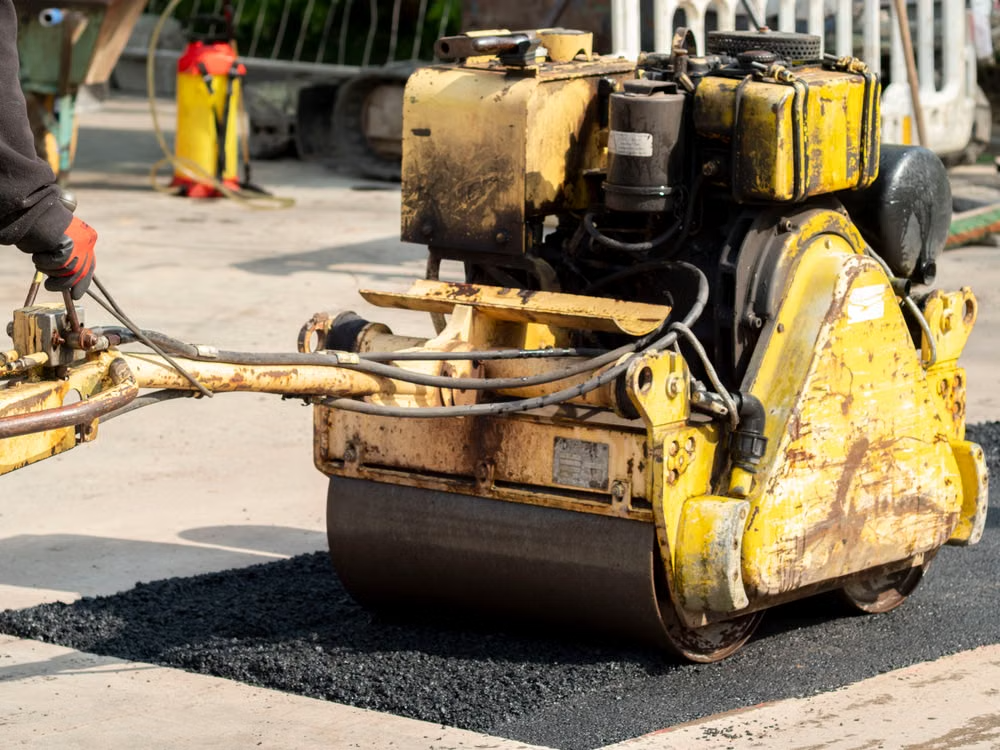 A road roller compacting asphalt during a repair and maintenance job